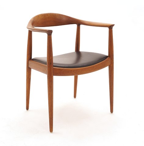 Hans J. Wegner, 1914-2007: The Chair i teak. 
Rygstykke med repareret brud. Se venligst foto. 
Stolen fremstår ellers stabil og brugbar. Sæde med 
sort læder