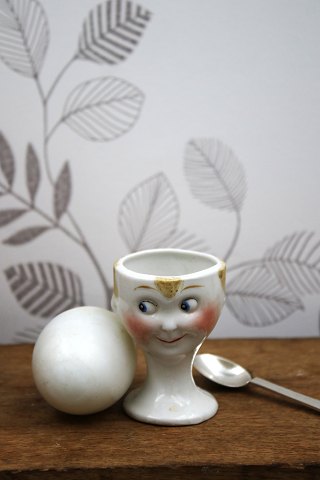 Old egg cup from the 1930s in porcelain with a painted funny face.