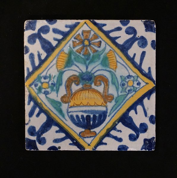 Polychromdekorierte holländische Fliese mit Blumenmotiv. Um 1620-40. Masse: 
13x13cm