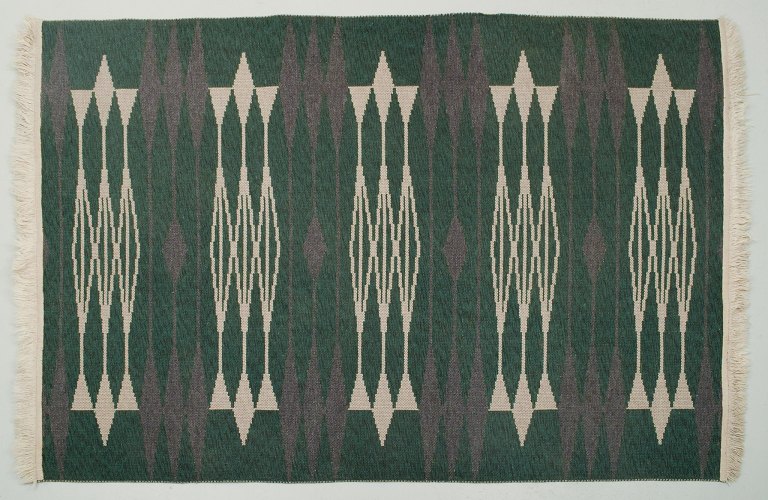 Swedish textile designer. Handwoven carpet in pure wool. Modernist design. 
Geometric fields in white and purple on a green background.