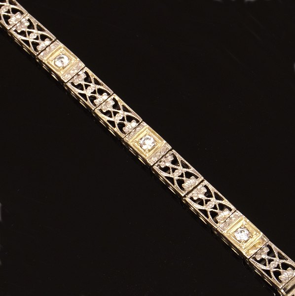 14kt hvidguld leddelt armlænke prydet med gennembrudte dekorationer og tre 
diamanter ca. 0,25ct i alt. L: 18,5cm. B: 4,5mm